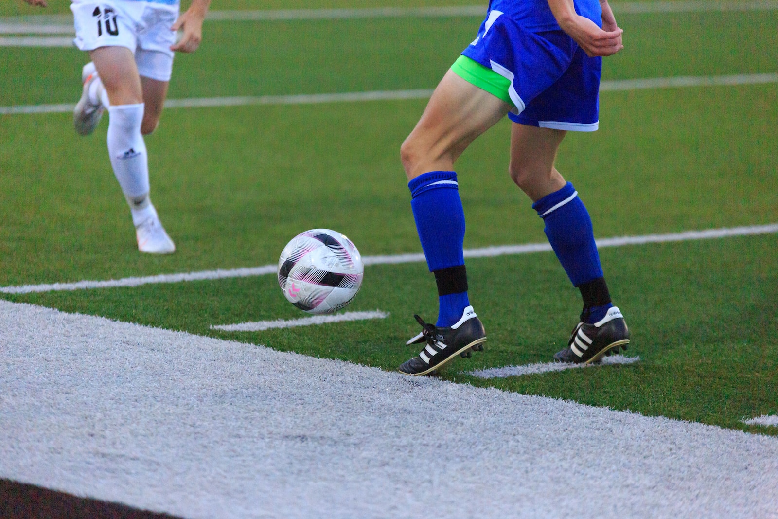 person in blue and white soccer jersey kicking soccer ball on field during daytime