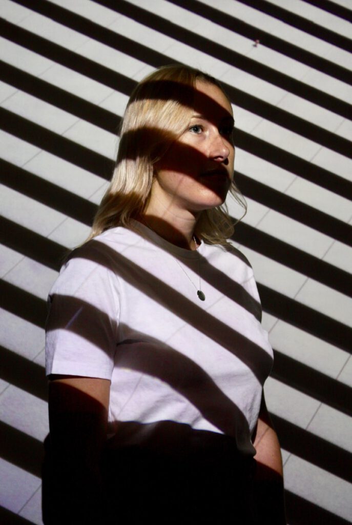 woman in white t-shirt beside wall